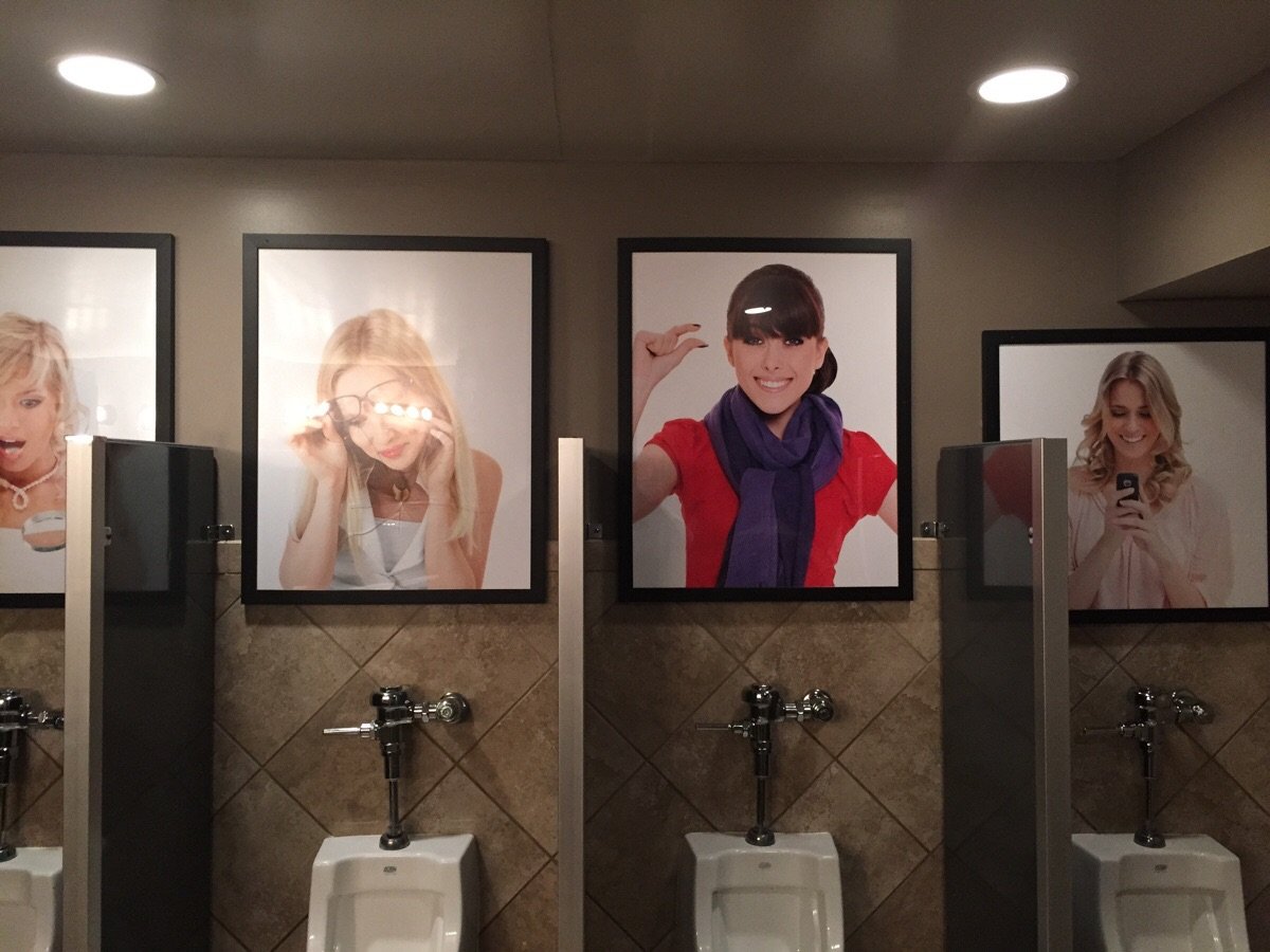 Pictures above the urinals at a bar.